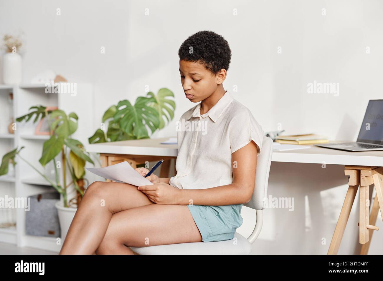 Minimal portrait of African American girl studying at home in white ...