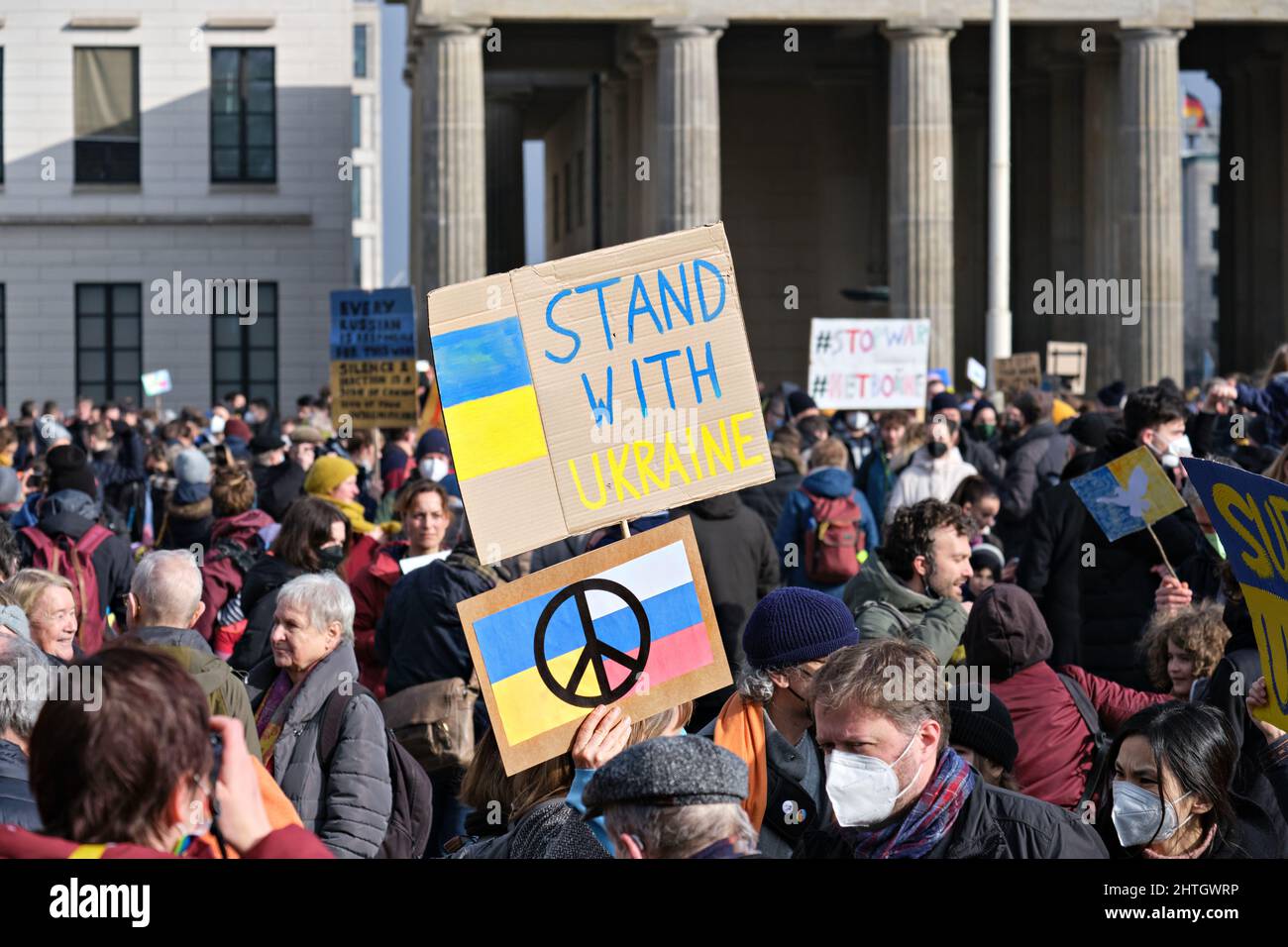 People with Ukrainian anti war placards protesting against the war in Ukraine by Brandenburg Gate. Stock Photo