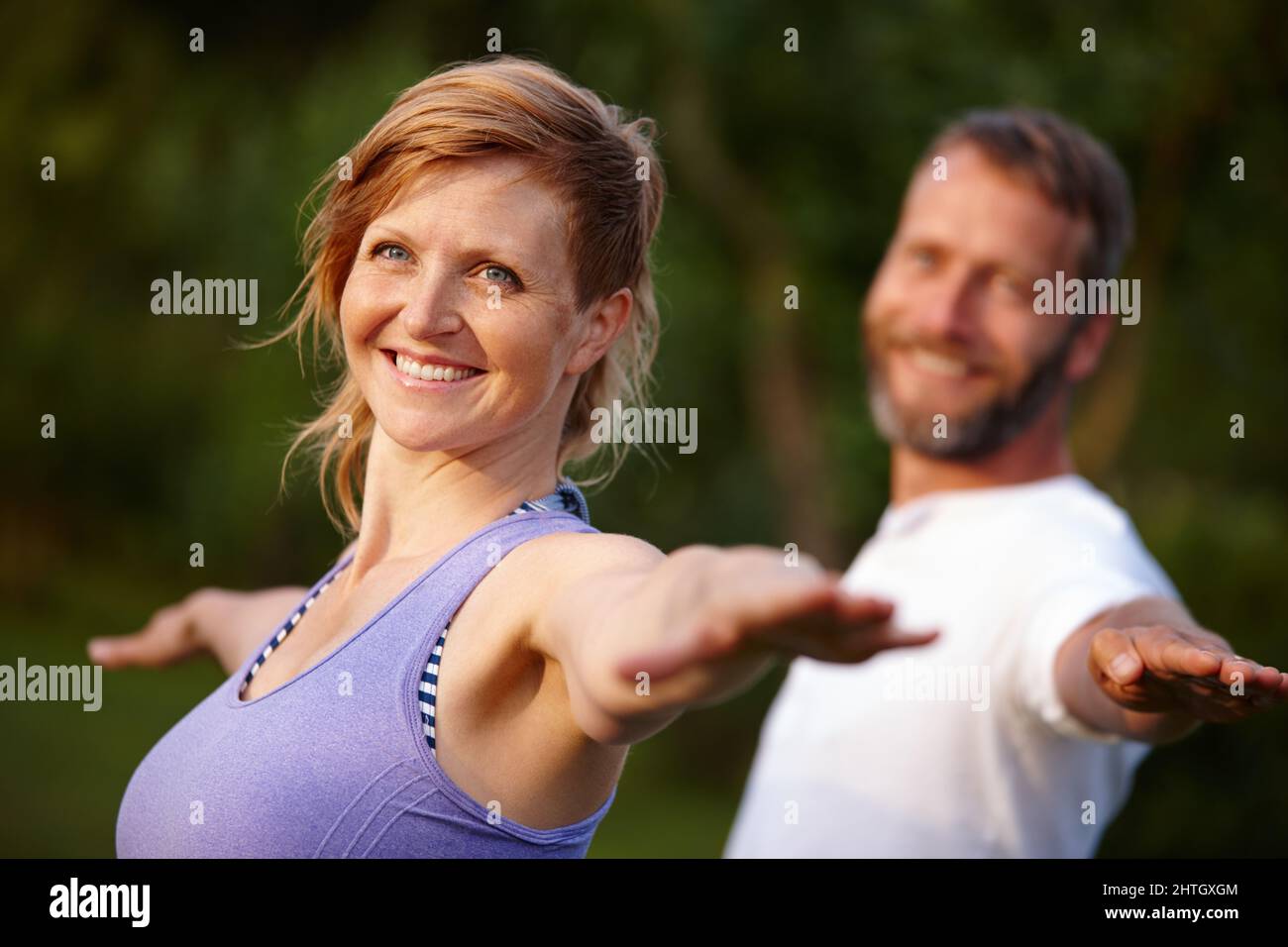 Staying in great shape. Shot of an attractive woman doing yoga with her partner in the outdoors. Stock Photo