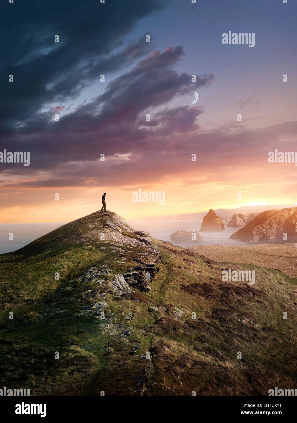 A man hiking to reach the top of a mountain summit at sunset along the UK coastline. Photo composite. Stock Photo