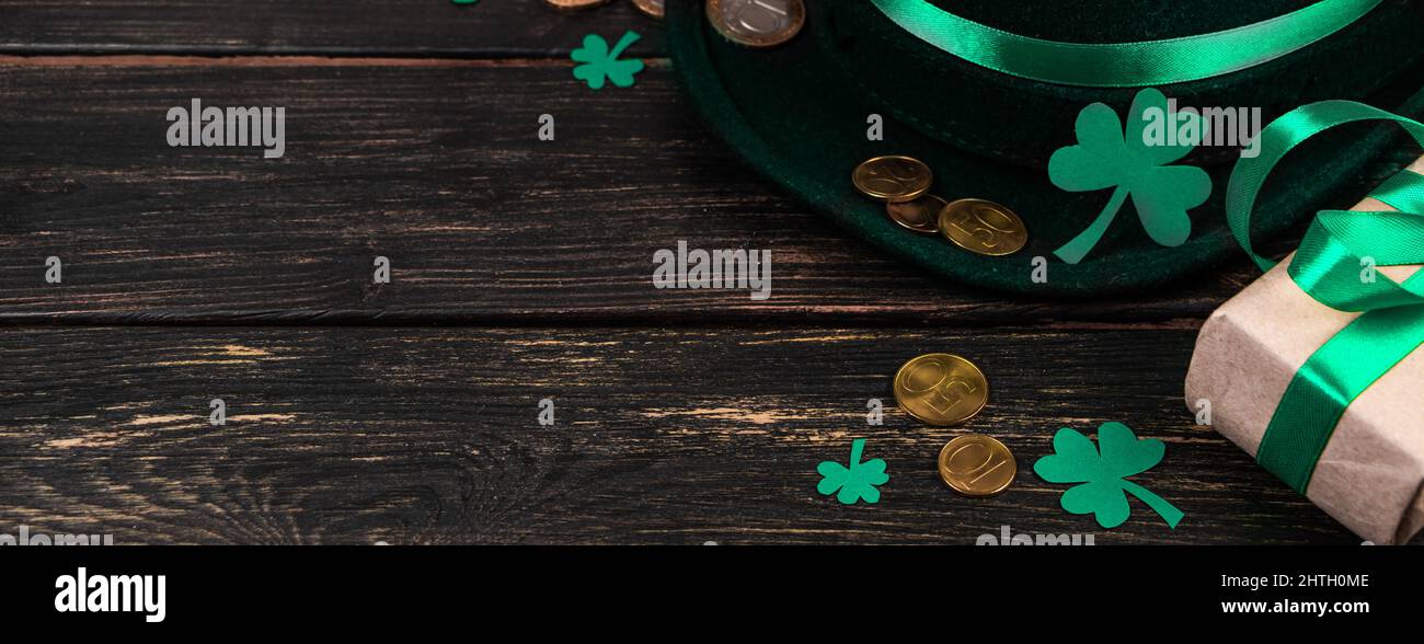 Leprechaun hat and shamrock clover leaves on brown wooden background. Happy St. Patrick's Day. Place for your text, banner format. Stock Photo