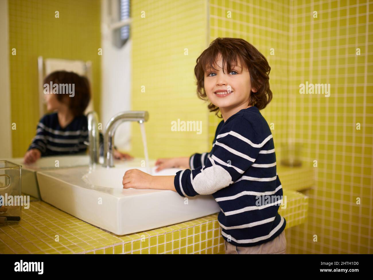 This is how Mom showed me to do it. A cute little boy washing his hands in the bathroom basin. Stock Photo