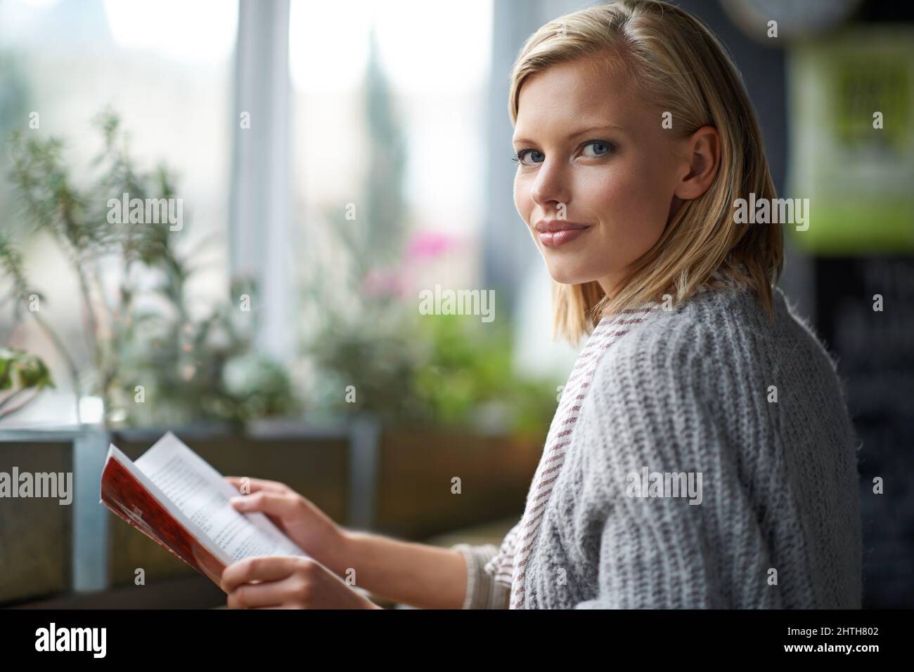 Relaxing with a book.... A young woman sitting in a coffee shop reading a book. Stock Photo