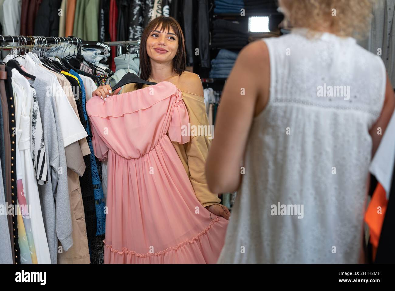 brunette girl trying on a dress in a clothing store, her friend advising, shopping in a mall, women's clothing showroom, girlfriends shopaholic lifest Stock Photo