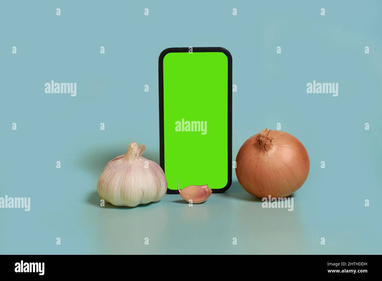 Online shopping. Smartphone with a green screen, garlic and onion Stock