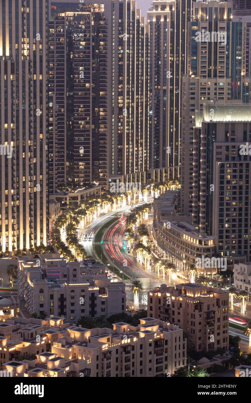 Traffic on a road between highrise buildings at night. Dubai, United Arab Emirates. Stock Photo