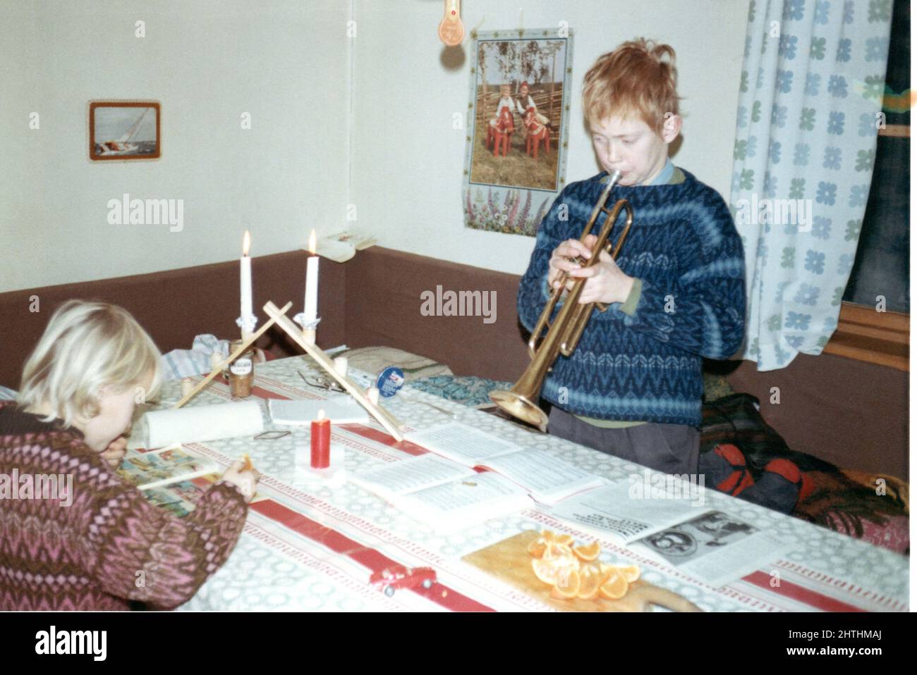1960's authentic vintage photograph of boy playing trumpet and girl reading, Sweden. Concept of family life, learning, hobbies Stock Photo