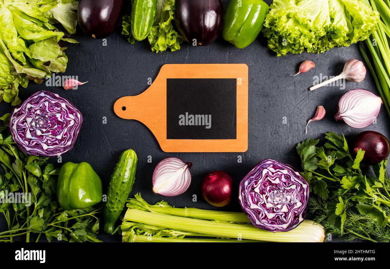 a frame of purple and green fresh vegetables on a black background. is