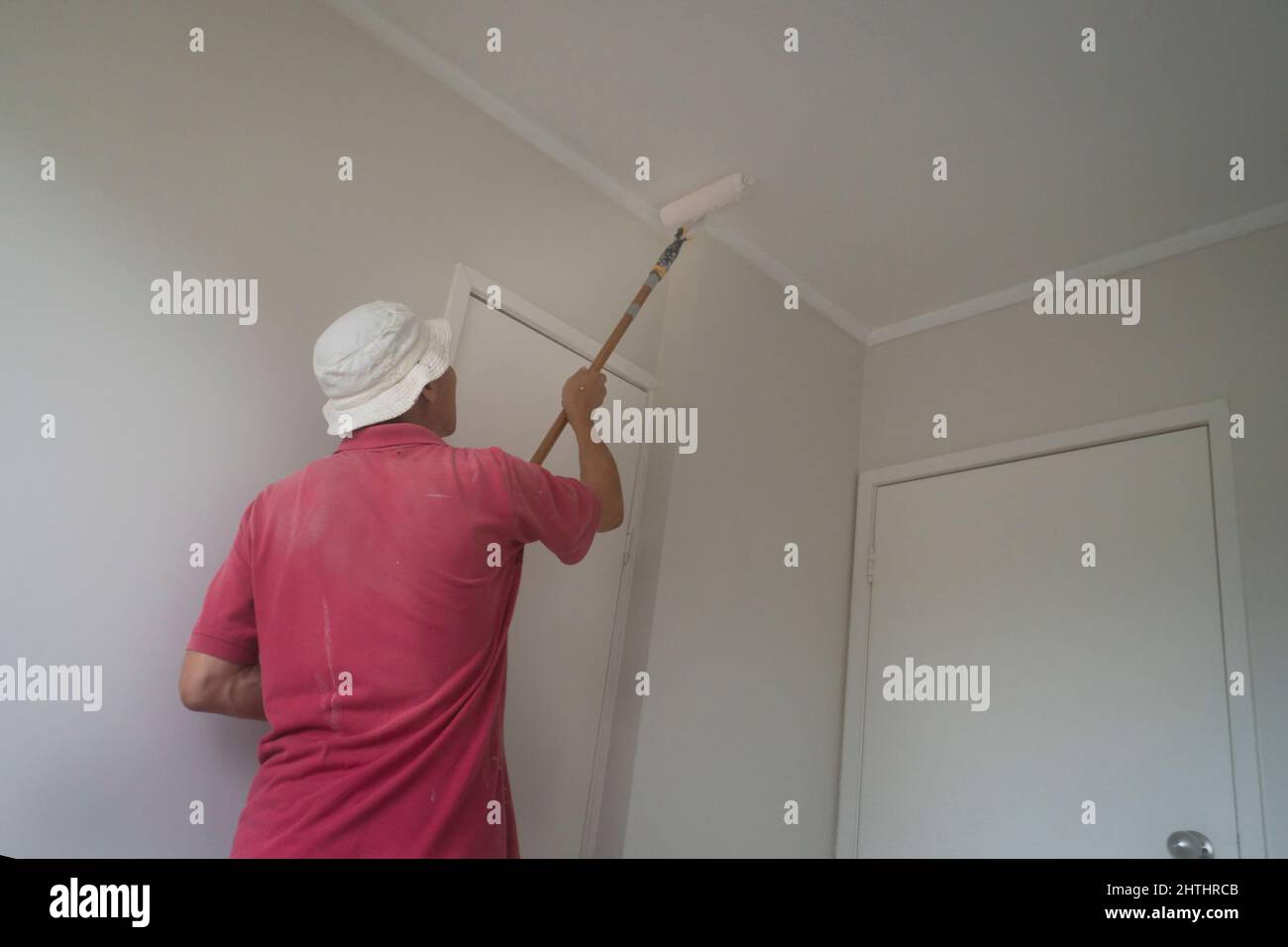 https://c8.alamy.com/comp/2HTHRCB/man-painting-ceiling-with-a-roller-in-new-home-2HTHRCB.jpg