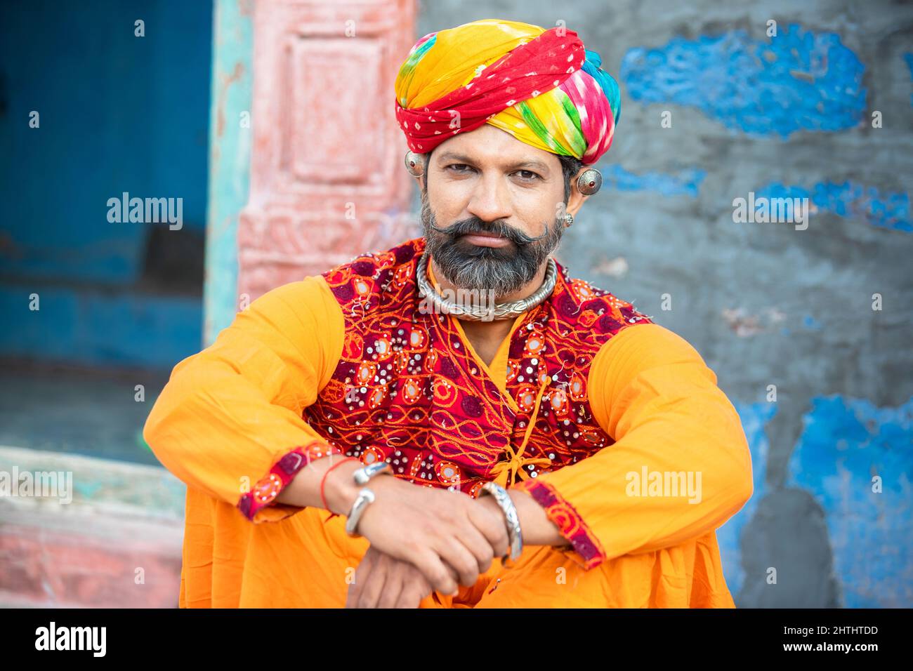 Portrait of happy traditional north indian man wearing colorful attire sitting. Smiling Rajasthan male with turban and ethnic outfits. Culture and fas Stock Photo