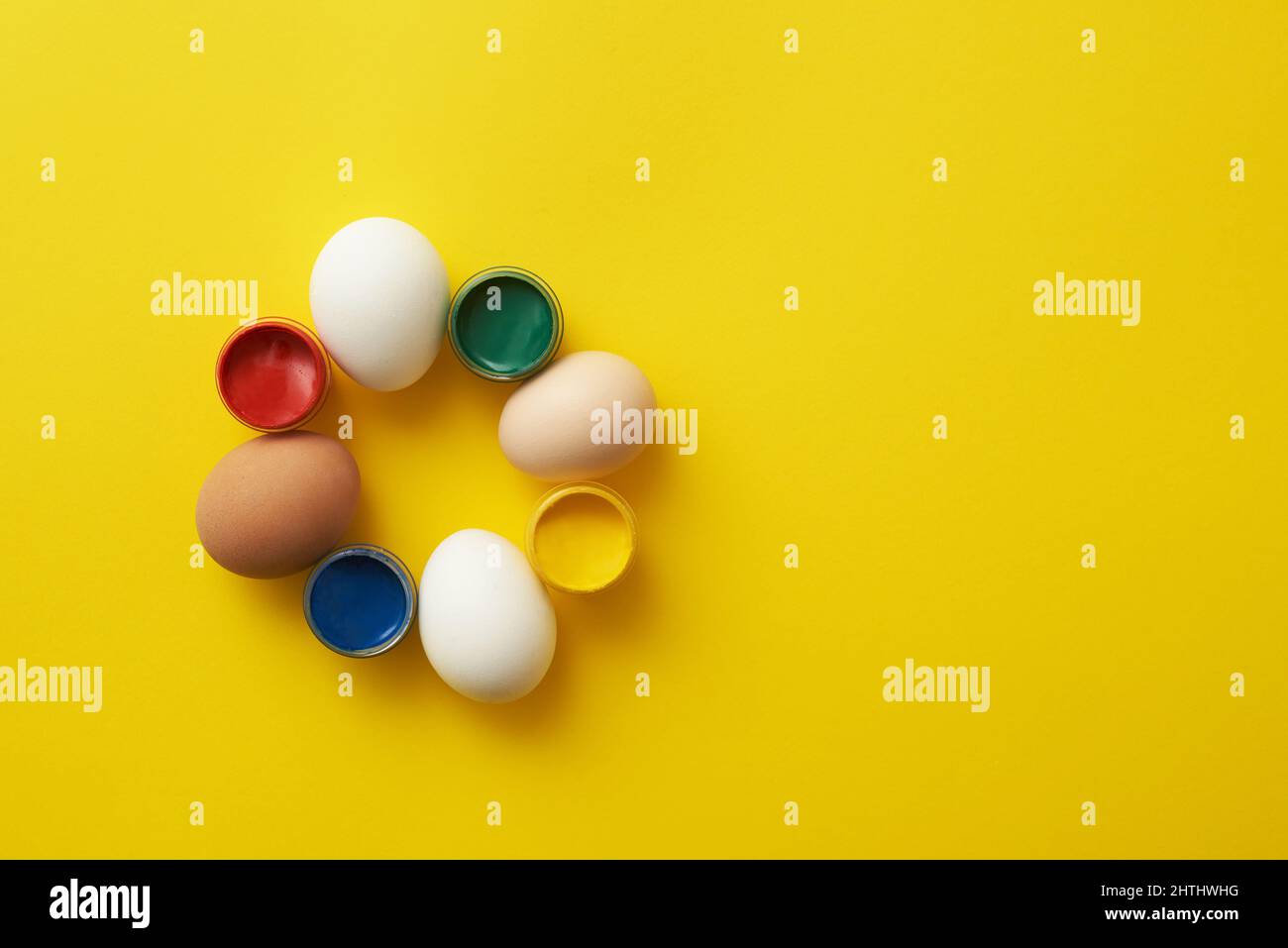 Chicken eggs and paints on a yellow background for colorful easter Stock Photo