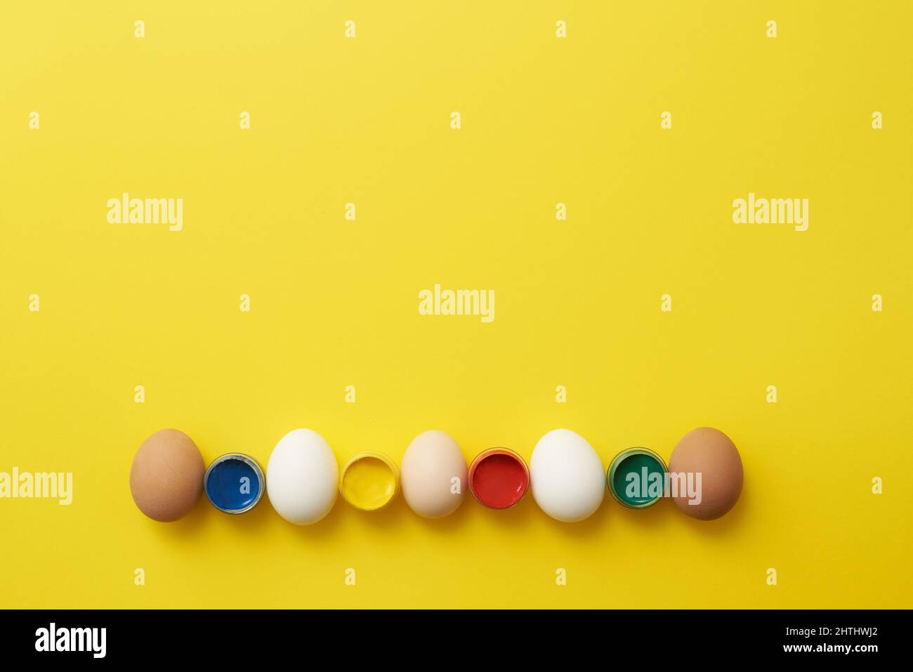 Chicken eggs and paints on a yellow background for easter Stock Photo