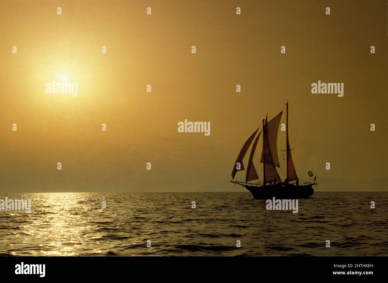 sailing boat goelette profile view on sunset yellow sun and sky background Stock Photo