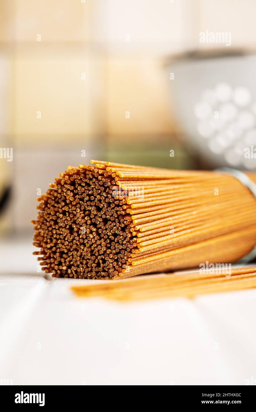 Uncooked whole grain spaghetti. Raw pasta on a white table. Stock Photo