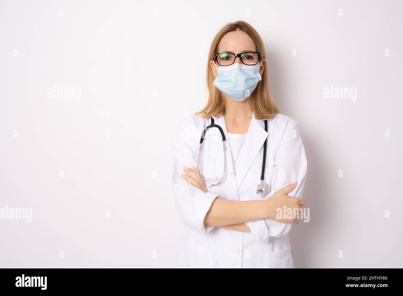 Confident woman doctor wearing medical mask standing with crossed arms ...