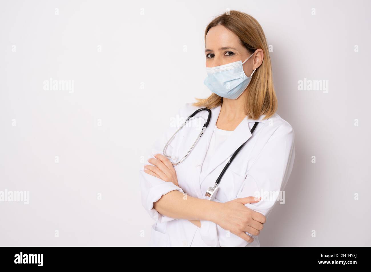 Confident woman doctor wearing medical mask standing with crossed arms ...