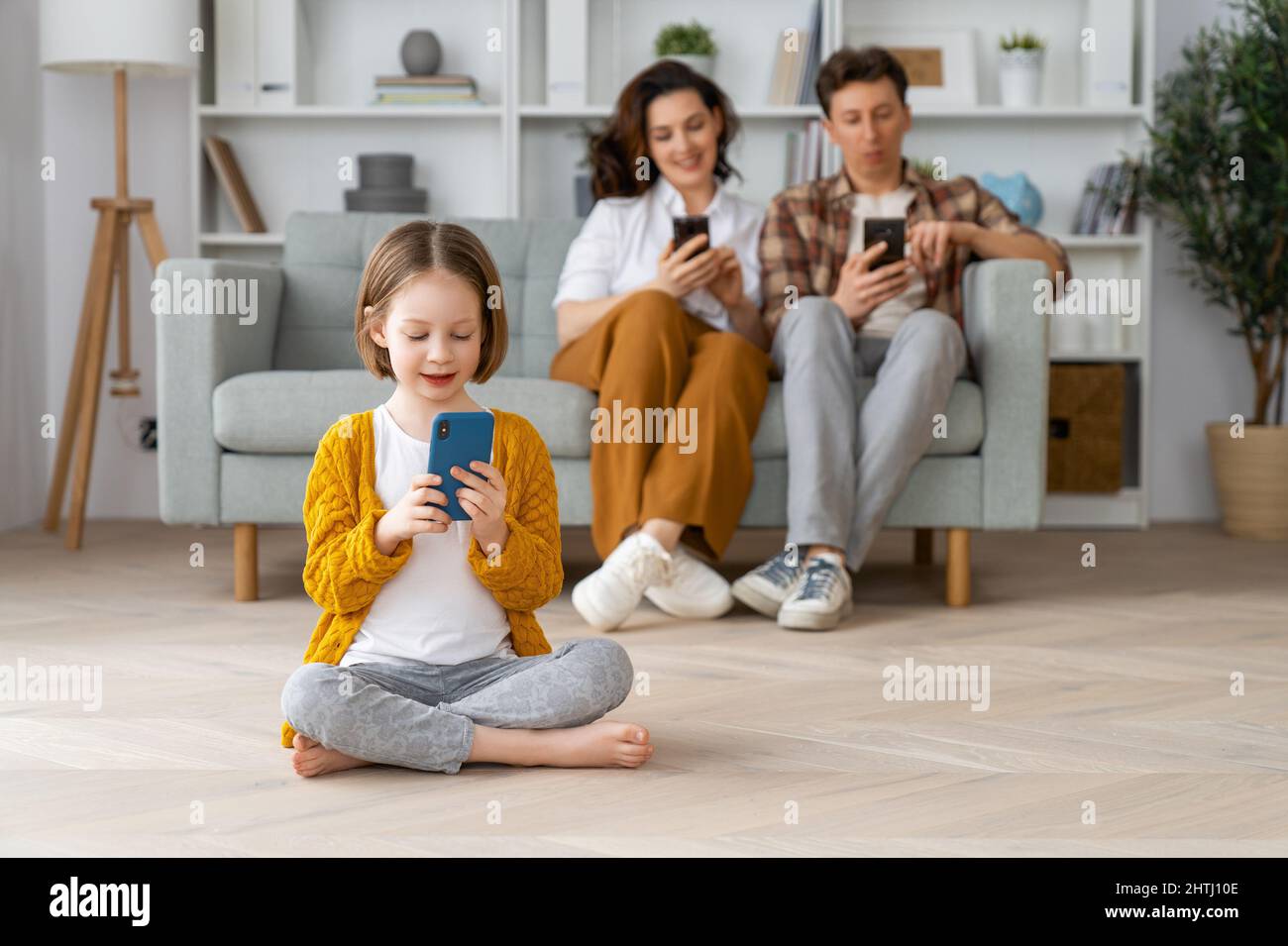 Happy loving family. Young mother, father and daughter using phones ...