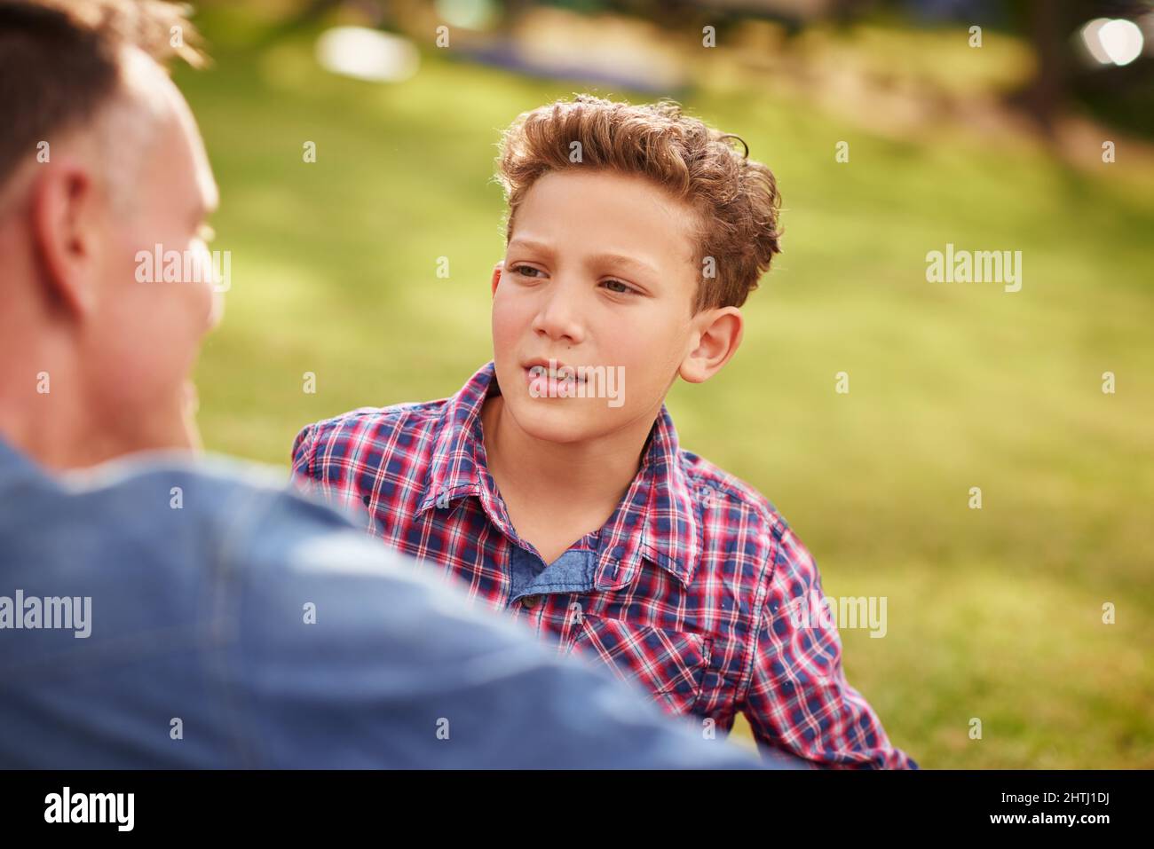 Having a heart to heart conversation with dad. Shot of a father and son talking together while lying in a park. Stock Photo