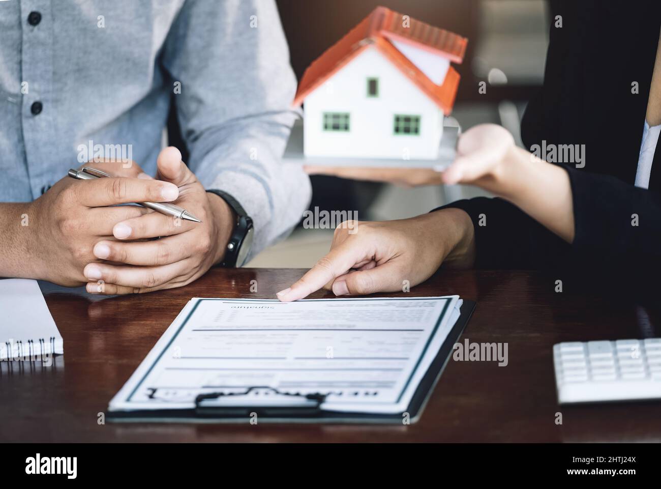 Loan signing concept, refinancing, home and land purchase, rental accommodation, female real estate agent or bank employee pointing to a contract or Stock Photo