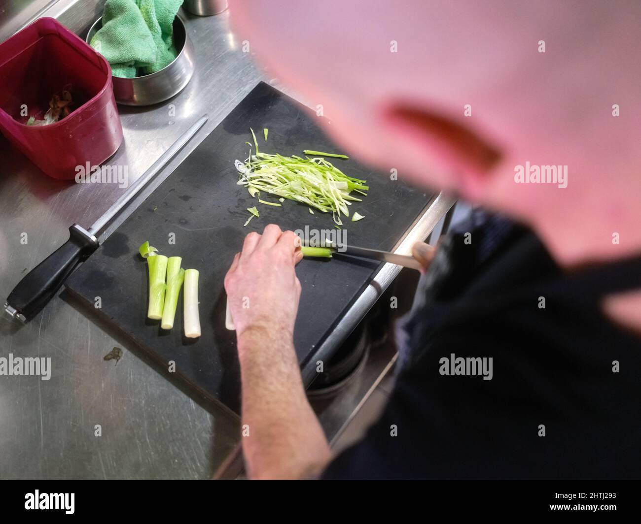 Cook cutting a celery using a sharp knife in a restaurant Stock Photo