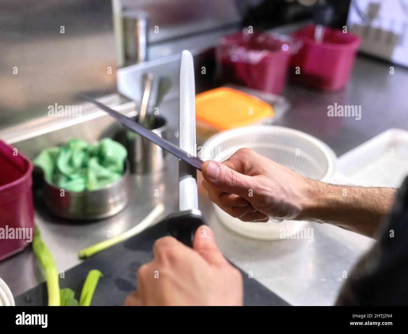Cook sharpening kitchen knives in a restaurant Stock Photo