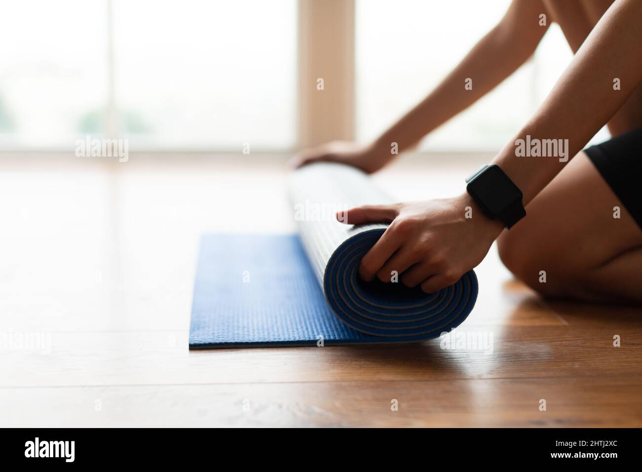 Young woman unrolling yoga mat on floor Stock Photo