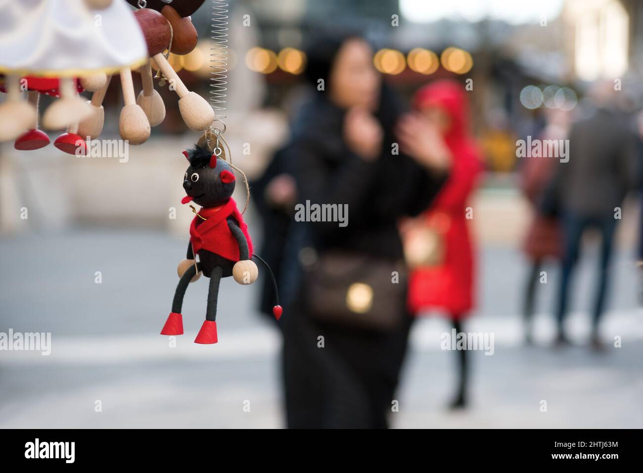 Toy devil against blurred woman walking, symbol of mood or behavior Stock Photo