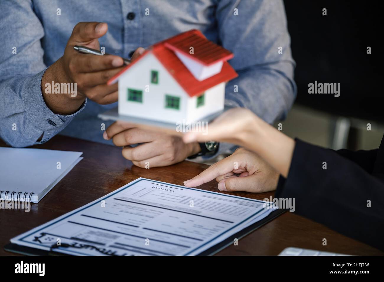 Loan signing concept, refinancing, home and land purchase, rental accommodation, female real estate agent or bank employee pointing to a contract or Stock Photo
