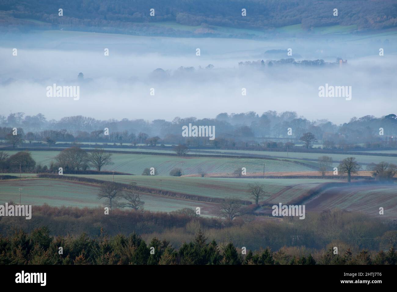 The Exe Estuary with an early morning mist covering most of Exmouth and Woodbury. The mist rolls and swirls as it cascades down into the low fields Stock Photo