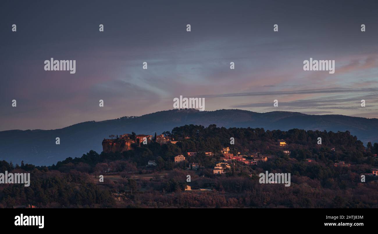 Roussillon village seen in the evening light with the luberon mountains in the distance . Stock Photo