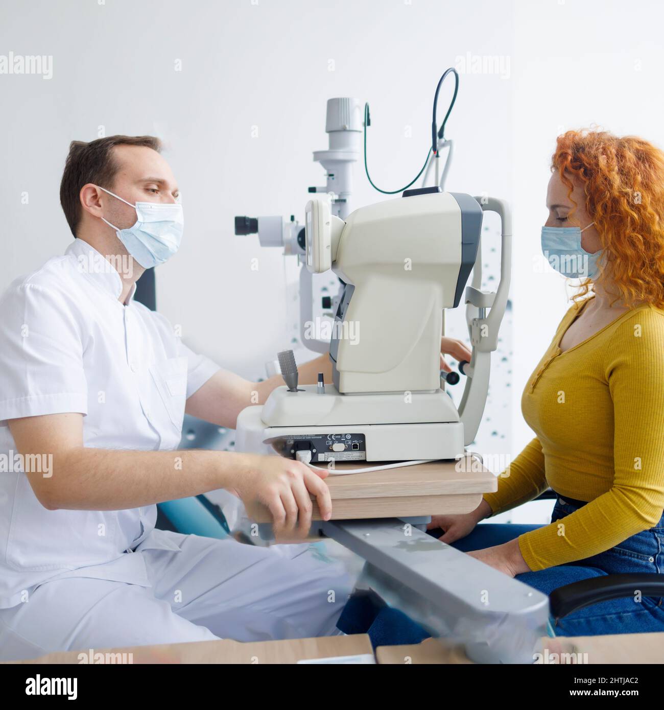 A doctor and his patient during an eye examination using autorefractor Stock Photo