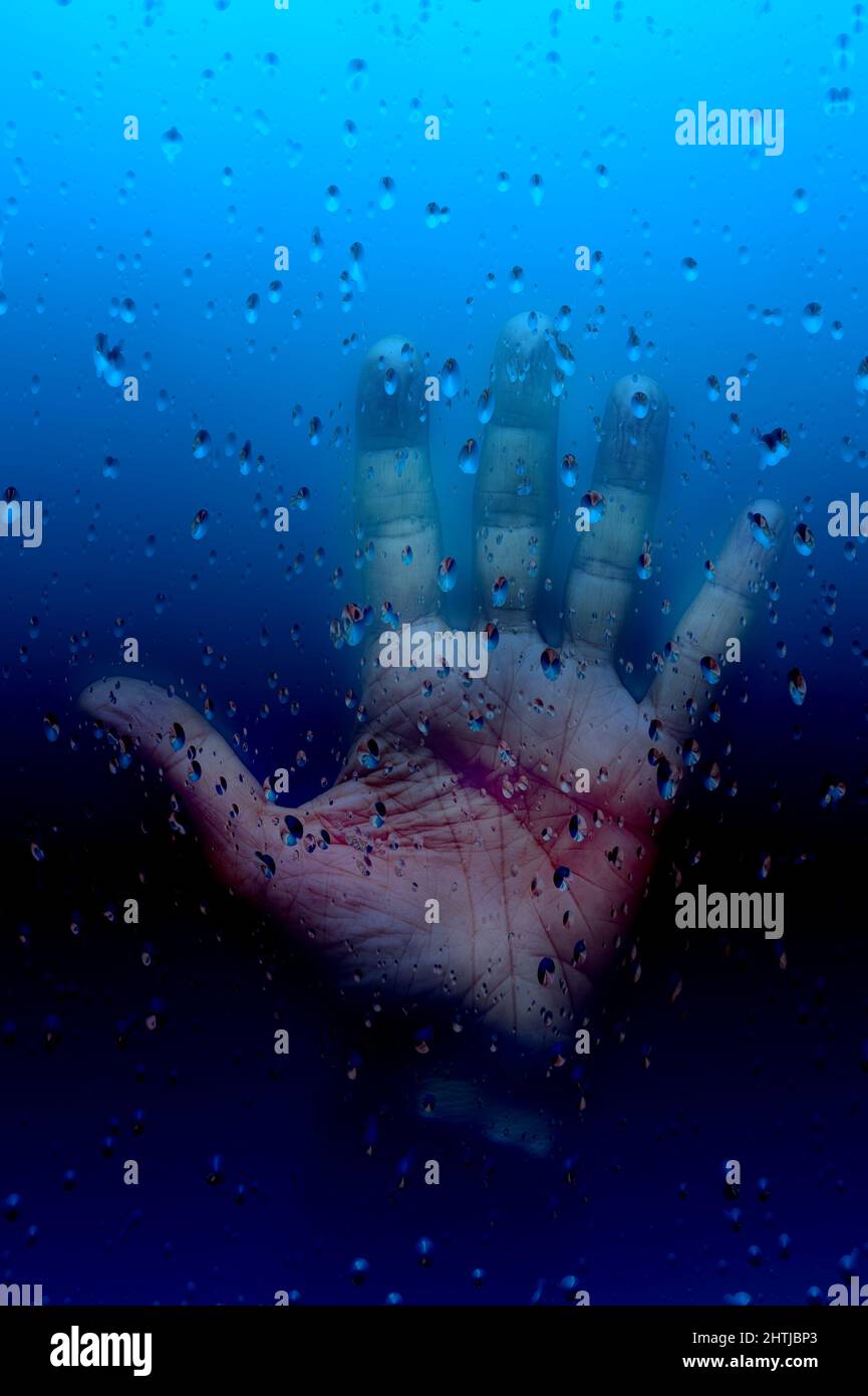 open hand behind a glass with water drops Stock Photo