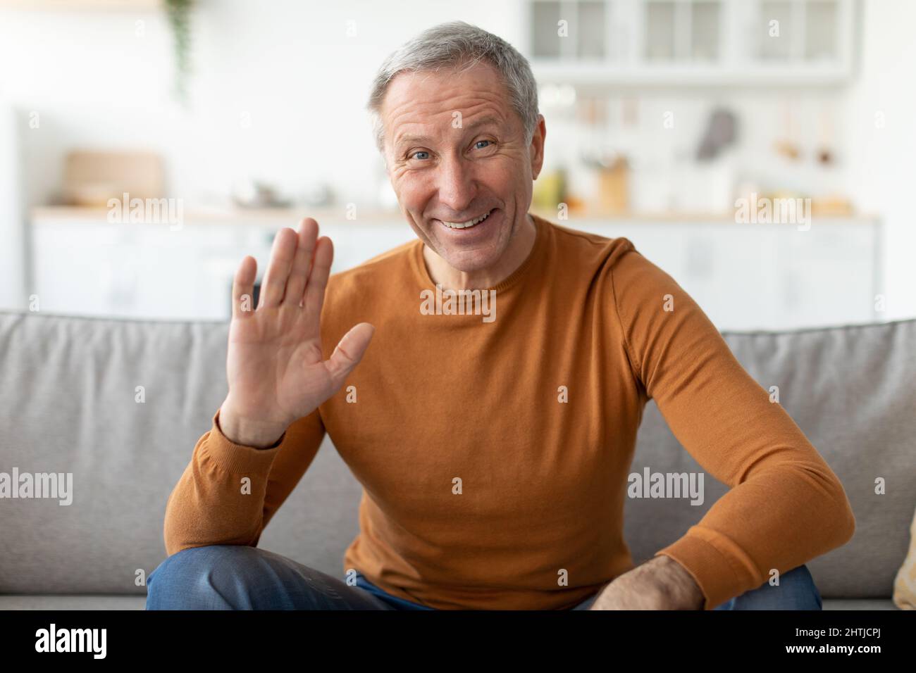 Greeting Concept. Mature man waving hand at camera Stock Photo
