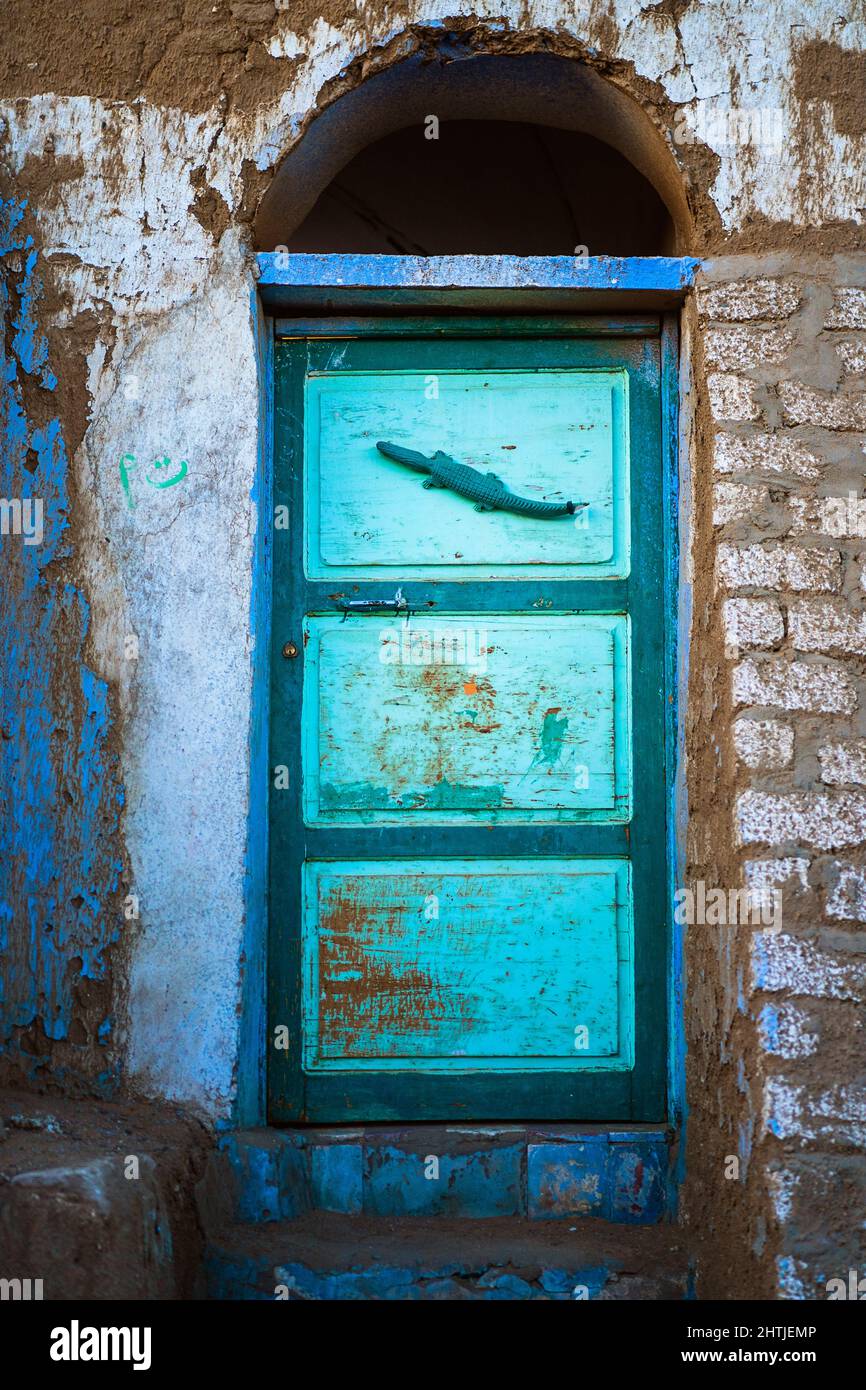 Bright painted door of neglected house with arched doorway and rough shabby wall located on street of town in Egypt Stock Photo