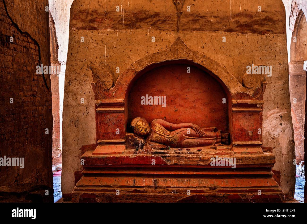 Ancient sculpture of sleeping Buddha placed at stone shabby wall located in Dhammayangyi temple in settlement of Bagan in Myanmar Stock Photo
