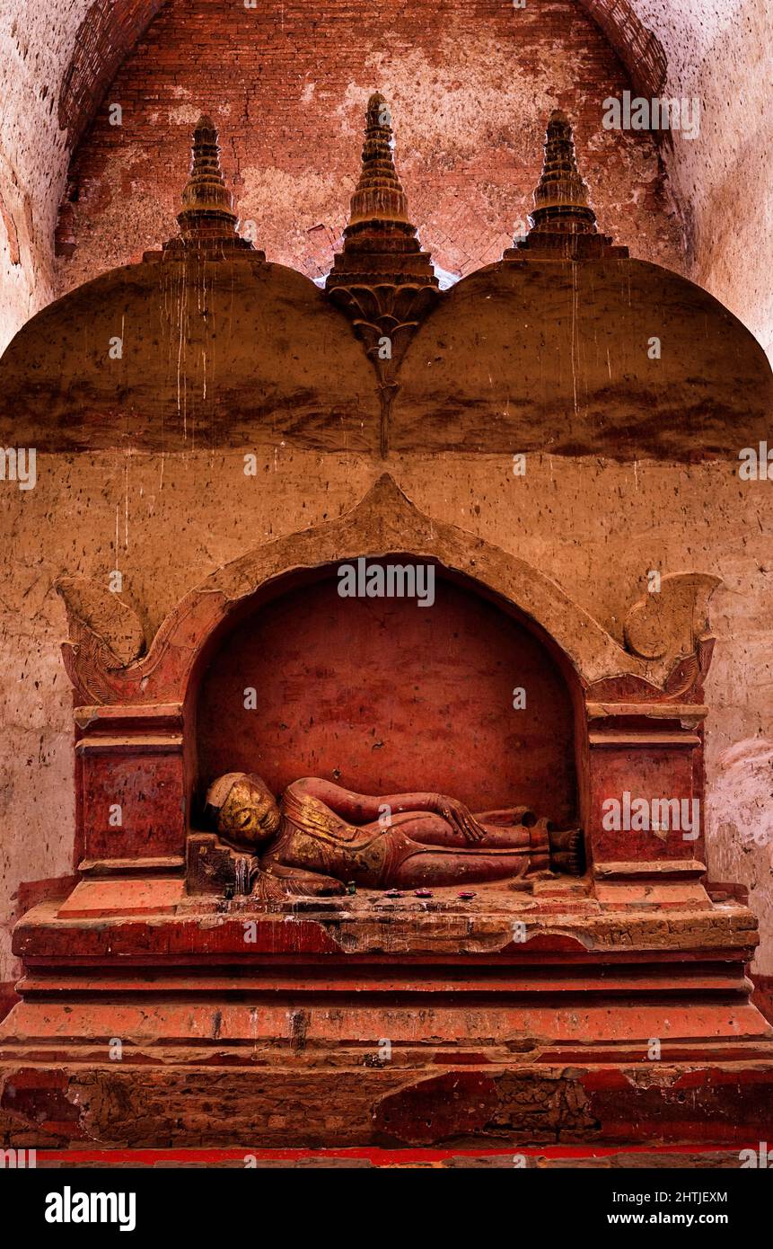 Ancient sculpture of sleeping Buddha placed at stone shabby wall located in Dhammayangyi temple in settlement of Bagan in Myanmar Stock Photo
