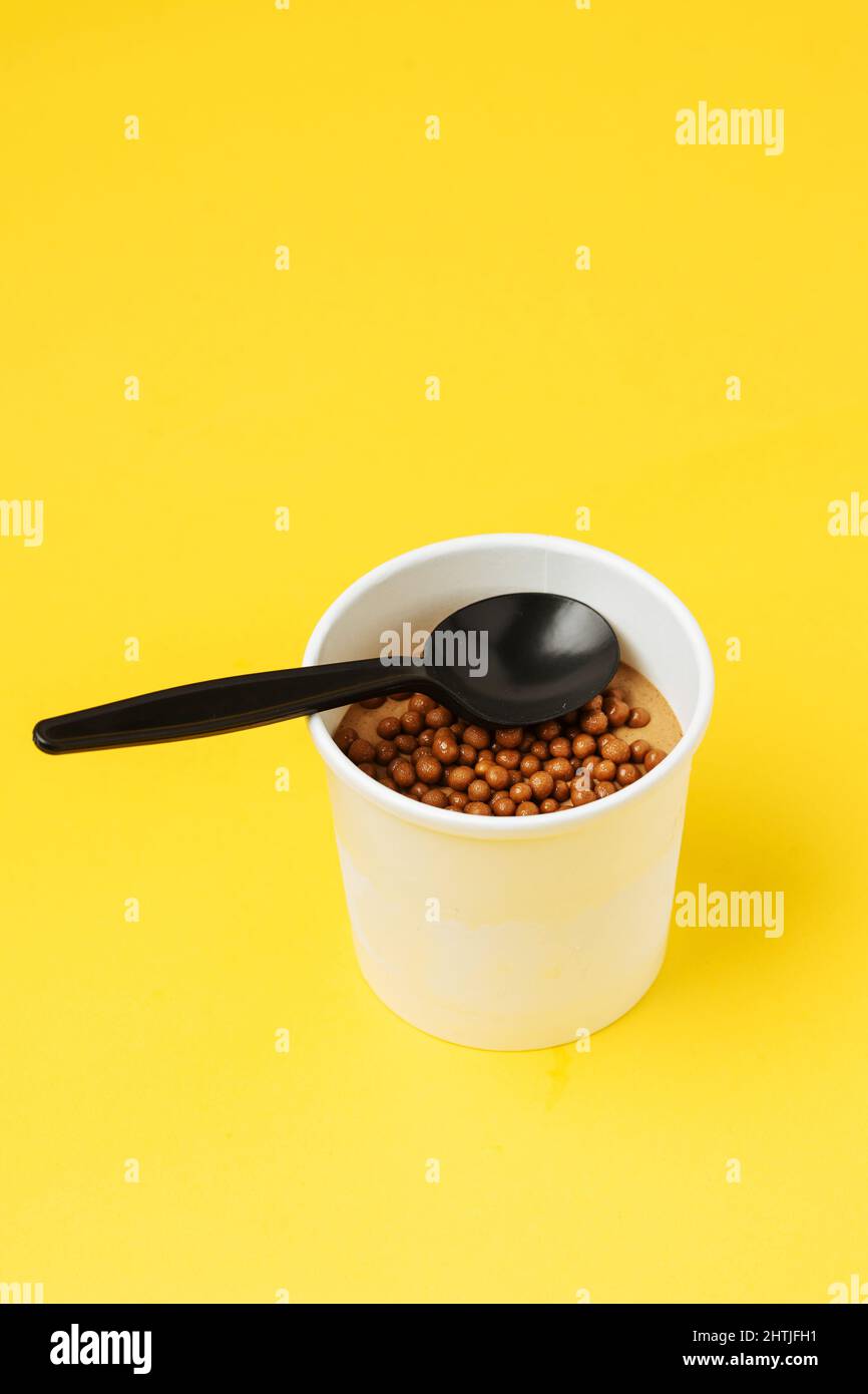 White paper tub filled with sweet chocolate ice cream topped with small