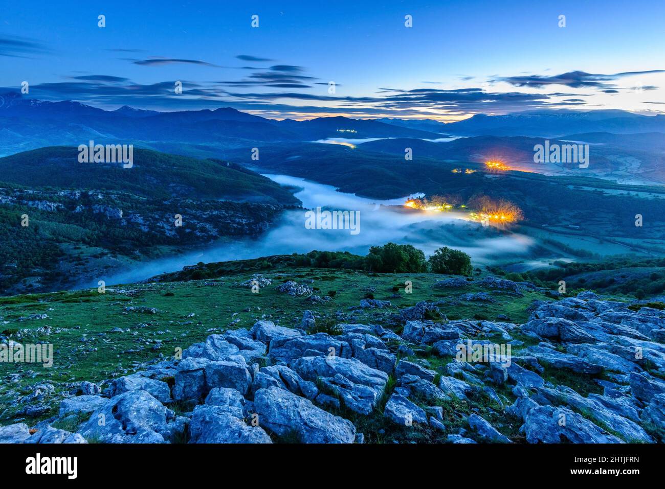 Breathtaking landscape of calm river flowing through mountainous valley in town under cloudy twilight sky in Palentian Mountains in Spain Stock Photo