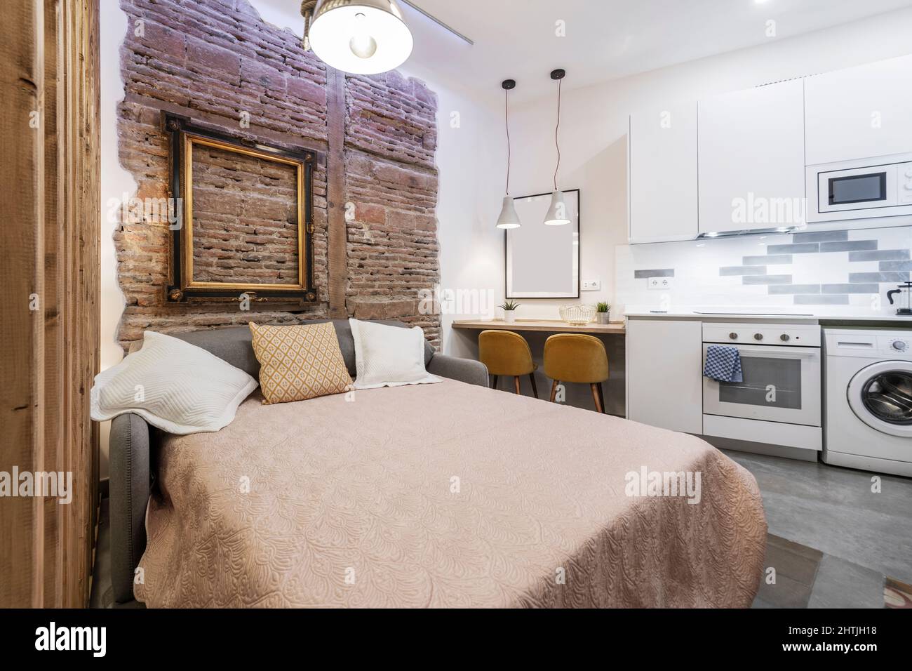 Nice living room with gray open sofa bed, exposed brick wall and study