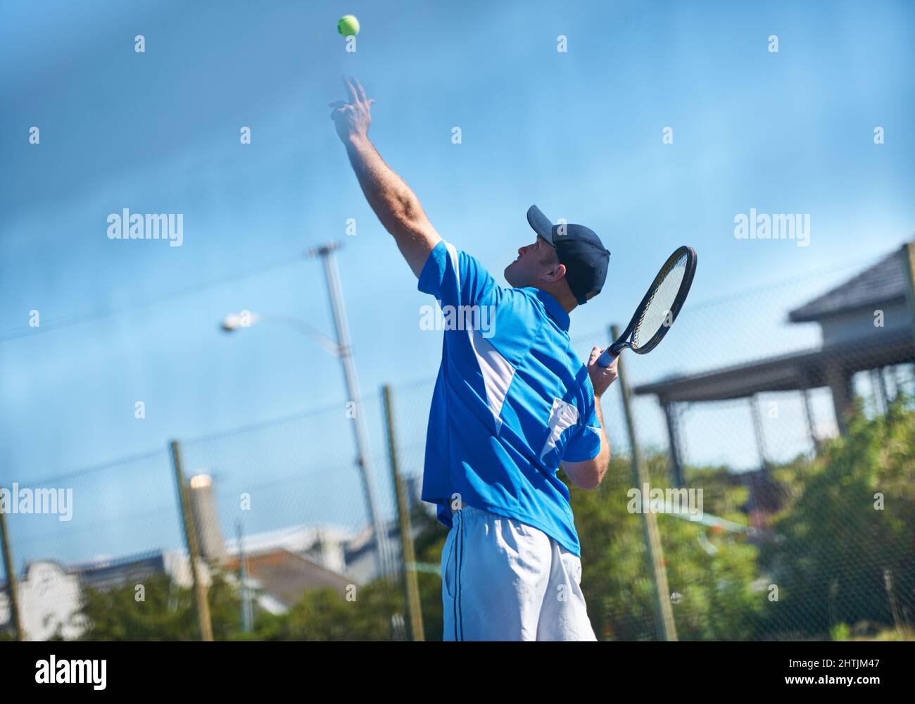 Blasting a serve. A male tennis player tossing the ball up into the air for a service - Tennis. Stock Photo