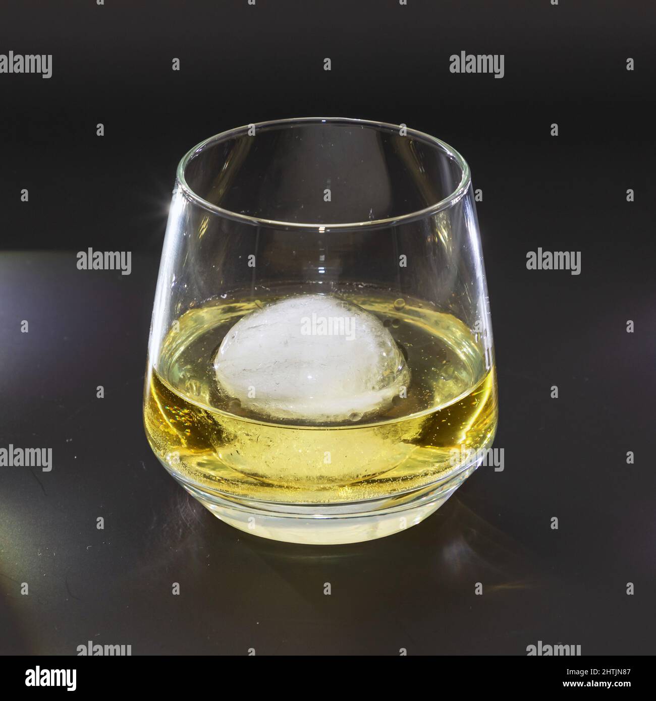 Whiskey on the rocks in a round drinking glass as studio shot with a black background Stock Photo
