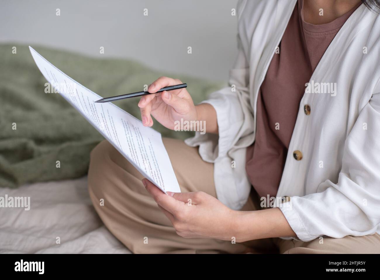 Young female auditor in casual apparel pointing at financial paper while looking through text and underlining main points Stock Photo