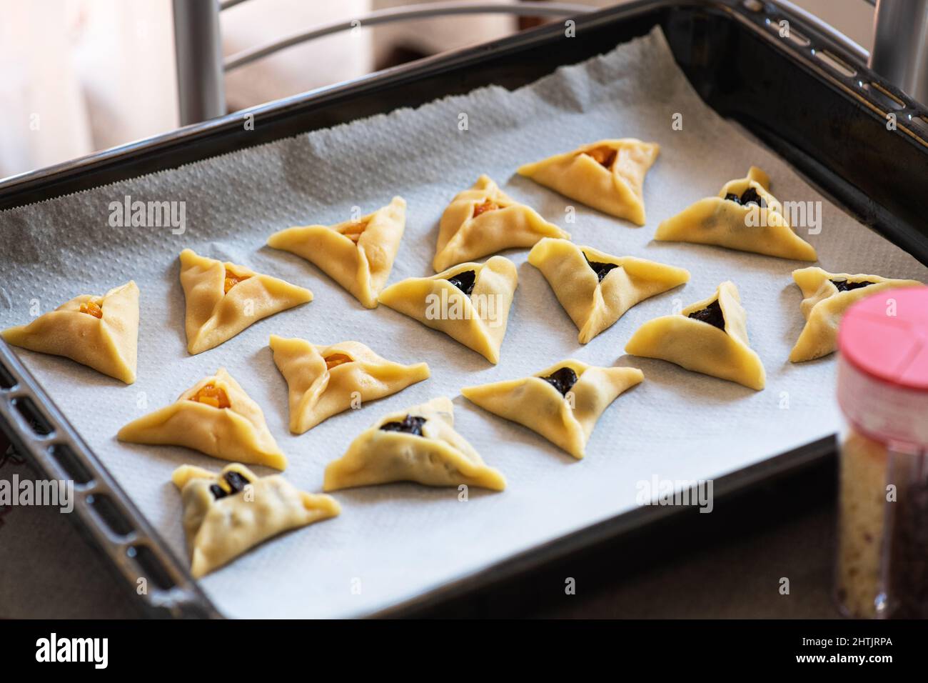 Hamantashen - traditional cookies for Purim, Jewish holiday. Triangle cookies  with different fillings on a baking sheet. Stock Photo