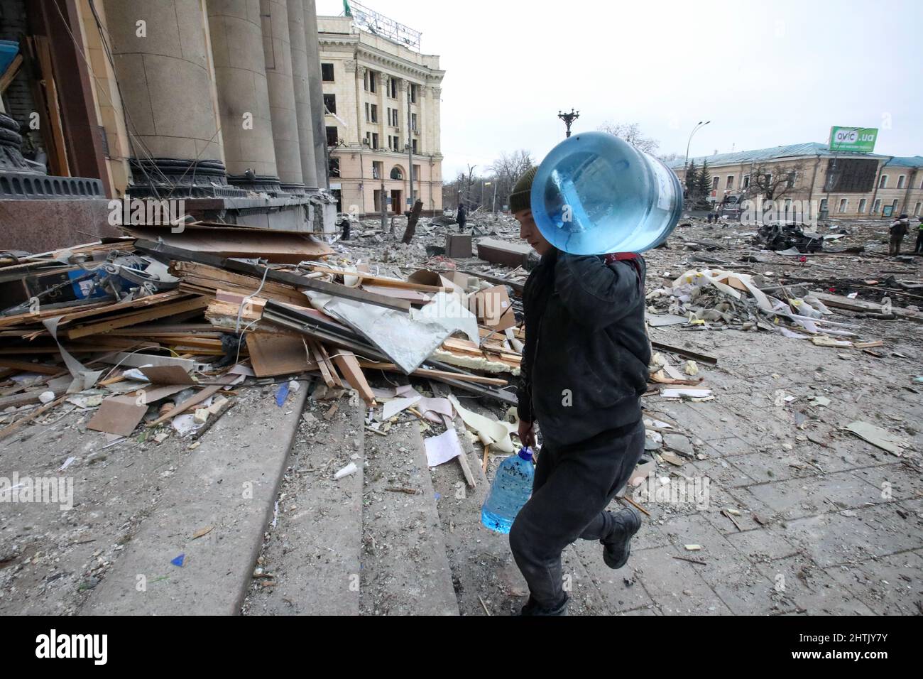 KHARKIV, UKRAINE - MARCH 1, 2022 - A man carries two bottles of water into the damaged building of the Kharkiv Regional State Administration after a missile launched by Russian invaders hit nearby in Svobody (Freedom) Square) at approximately 8 am local time on Tuesday, March 1, Kharkiv, northeastern Ukraine. Credit: Ukrinform/Alamy Live News Stock Photo