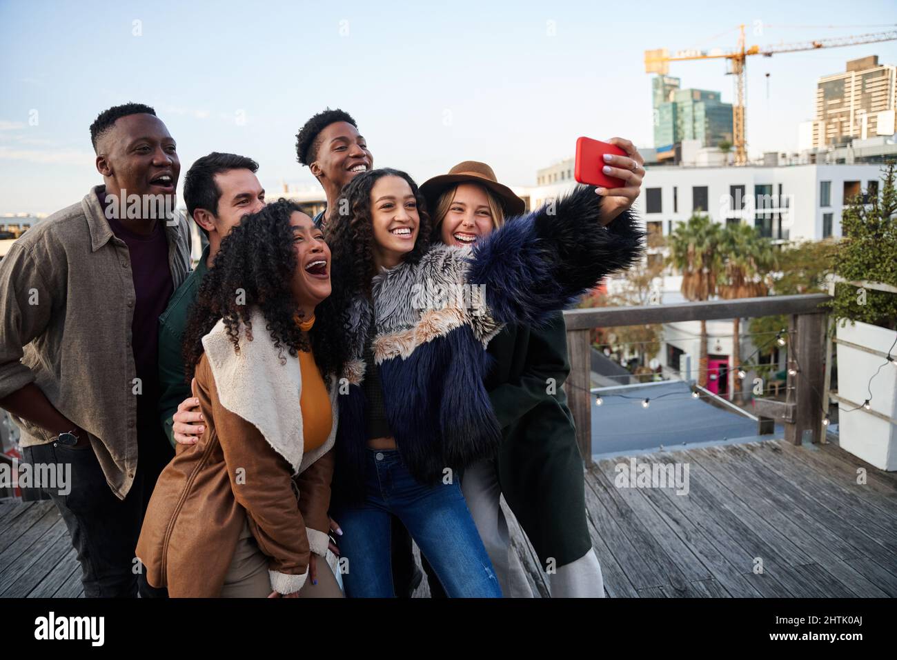 Multi-cultural group of friends taking a selfie at a rooftop party ...