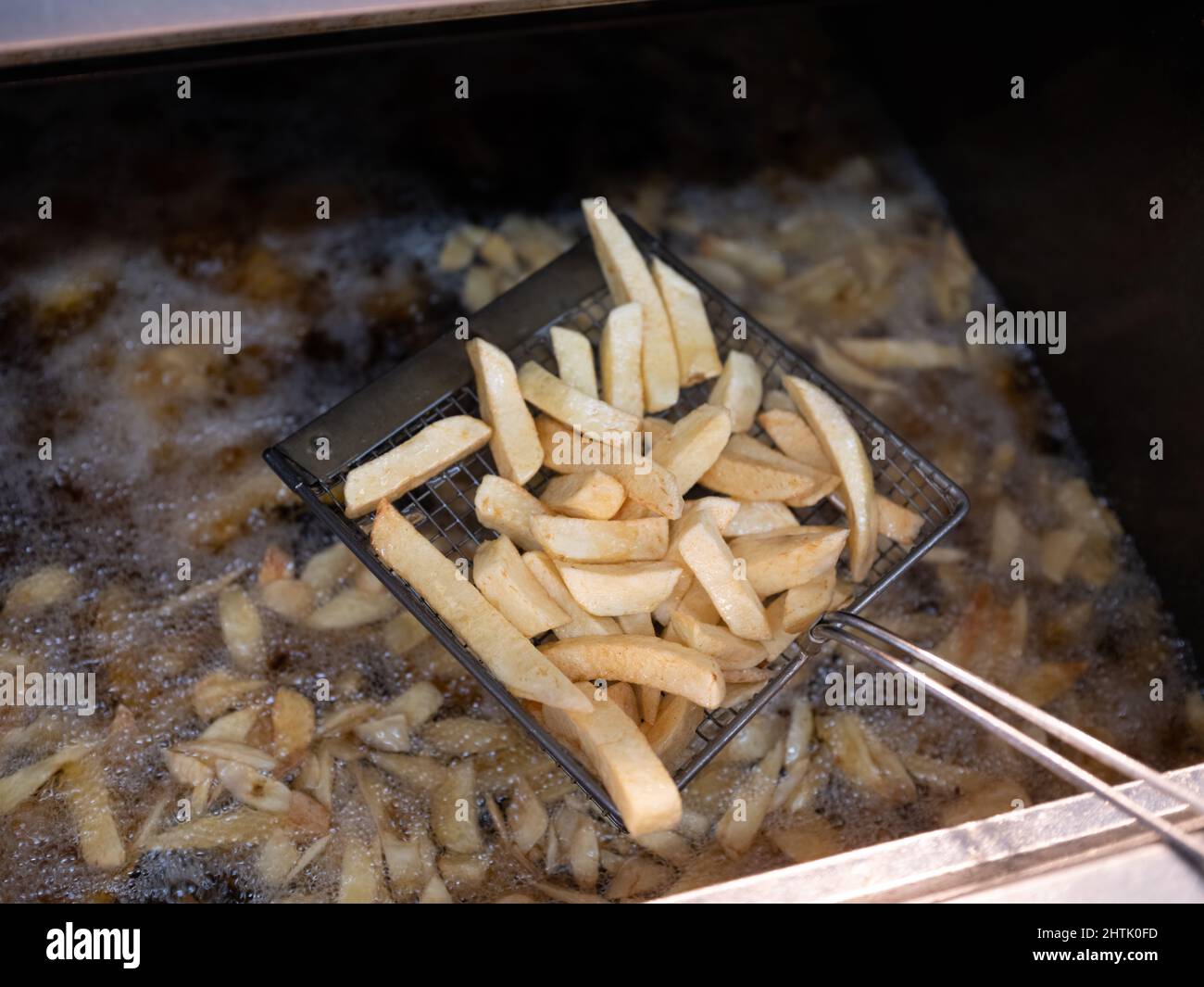 Potatoes cooking by frying in hot beef fat frier. Stock Photo