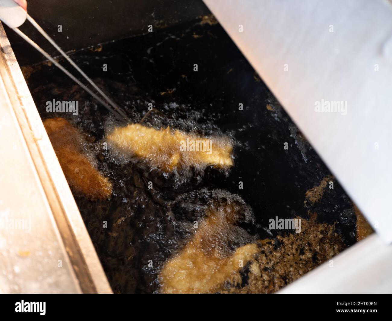 Fresh cod cooking by frying in hot beef fat frier, at Compo's fish and chip shop and restaurant, Holmfirth, West Yorkshire. Stock Photo
