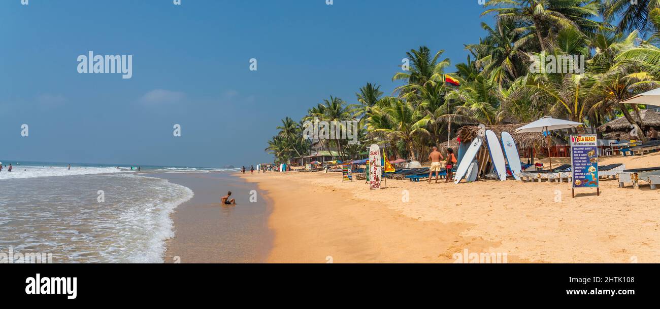 HIKKADUWA, SRI LANKA - JANUARY 22, 2022: Narigama beach at Hikkaduwa with people walking along the coastline with palmtrees Stock Photo