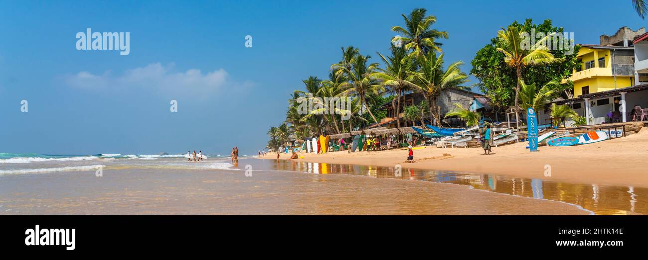 HIKKADUWA, SRI LANKA - JANUARY 22, 2022: Unidentified people on the beach at Hikkaduwa. Narigama surfer beach, panorama Stock Photo