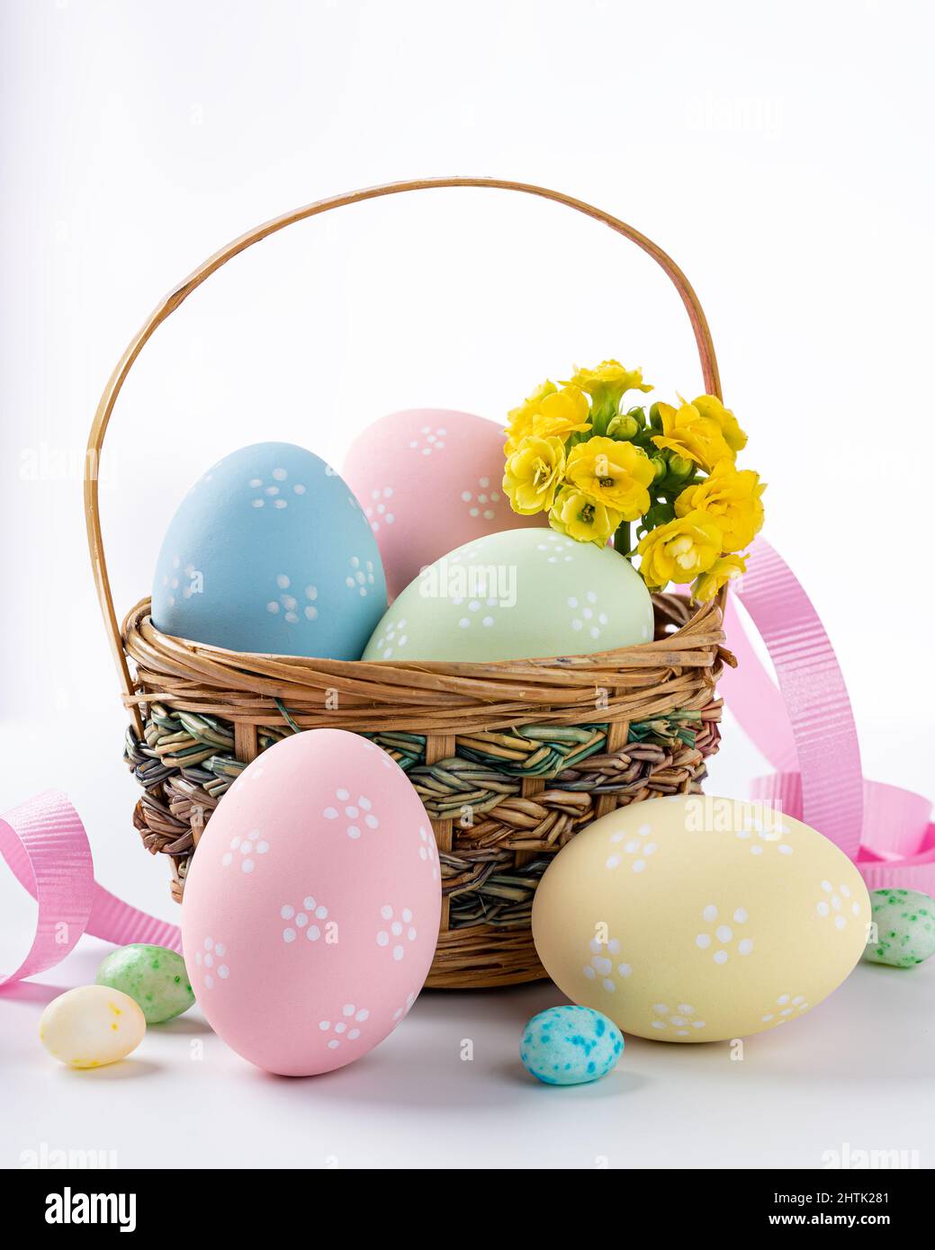 Colored easter eggs and flowers in a basket and on a white background Stock Photo